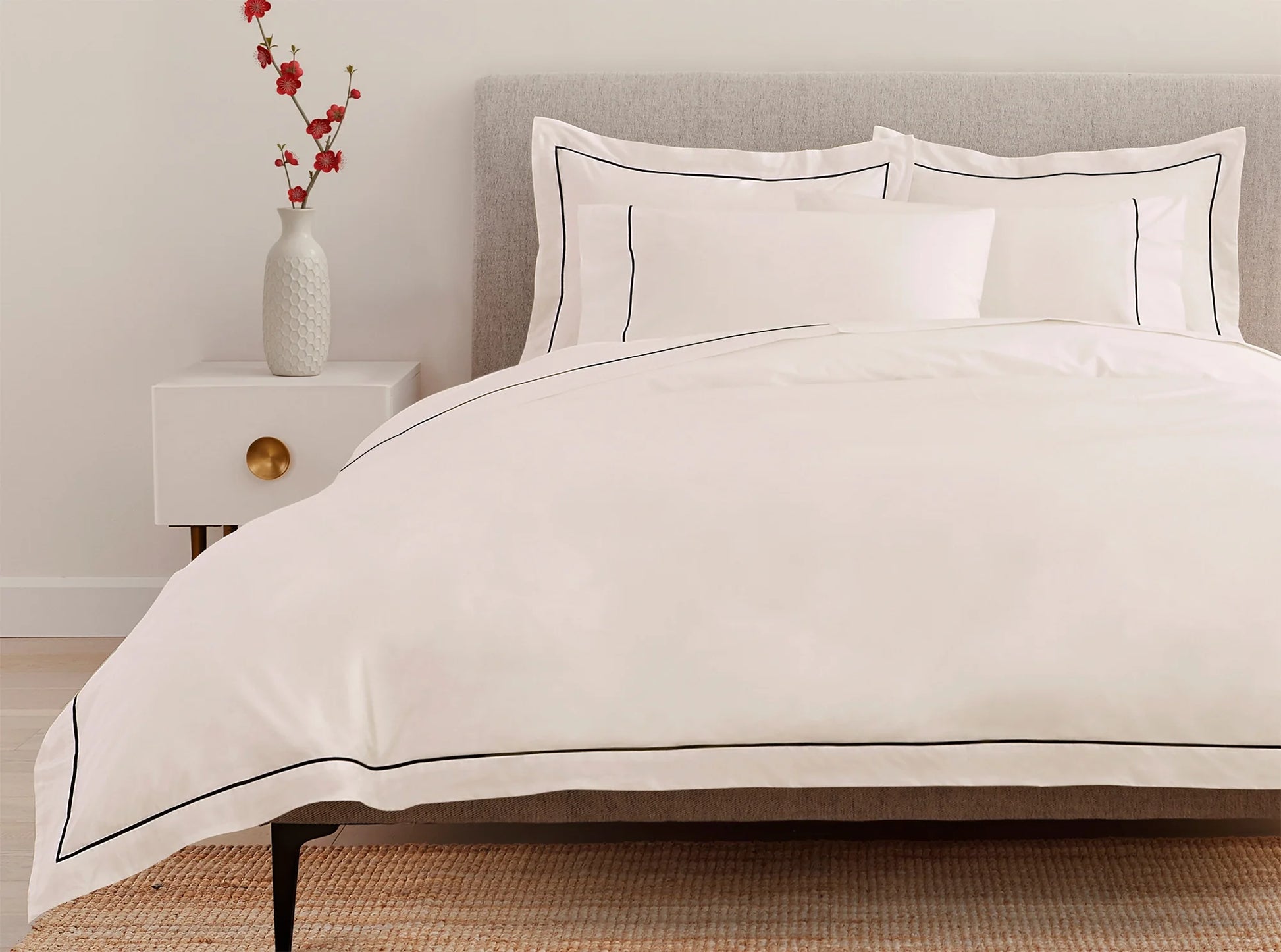 White percale duvet cover with navy embroidered detail on the bed - elegant contrast