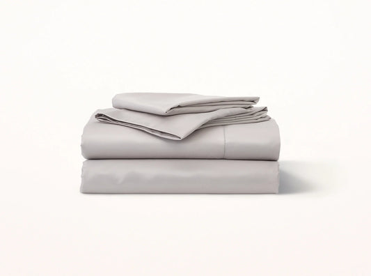 Organic cotton sateen hemstitched sheet set in quiet gray on bed - luxury bedding made in Portugal