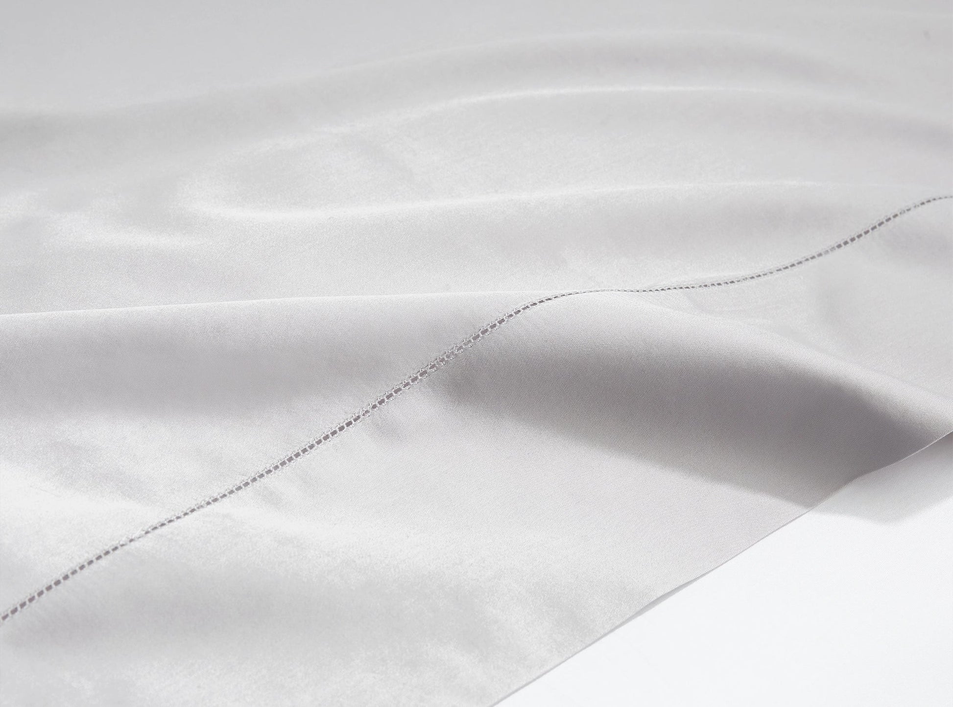 Close-up of hemstitched detail on organic cotton sateen sheets in quiet gray - handcrafted quality