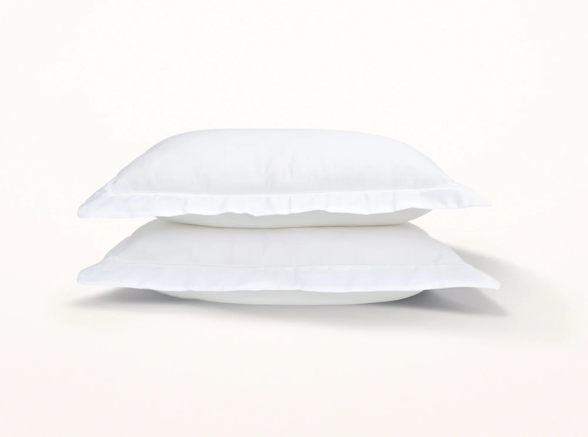 White organic cotton sateen pillowcases stacked, showing hemstitched detail and soft texture
